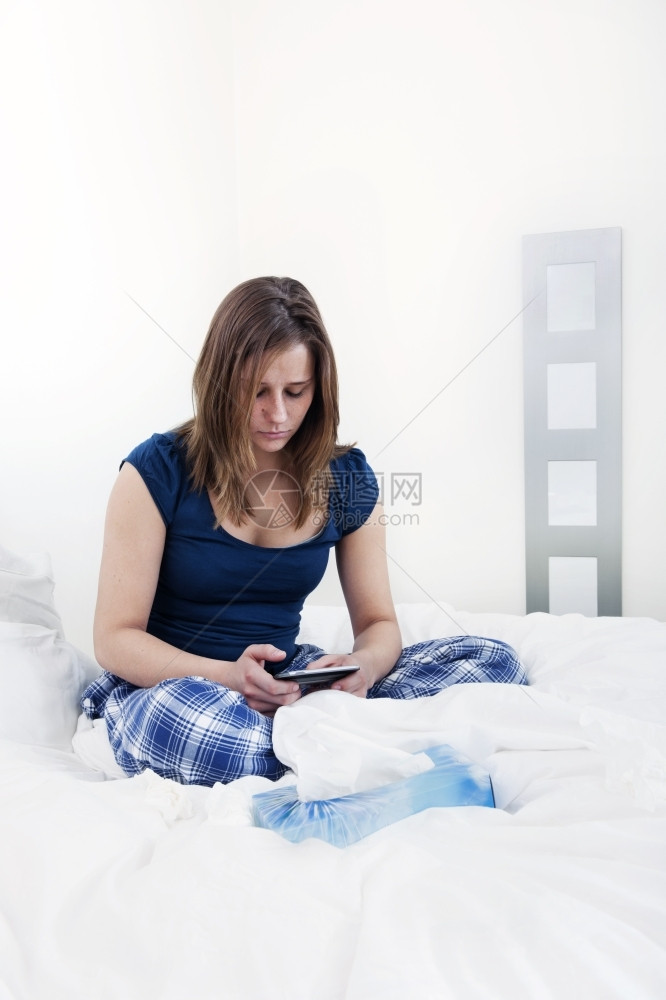 黑发地位社会的穿着睡衣年轻女青在家中生病时发信息上网看社交媒体站在家中生病图片