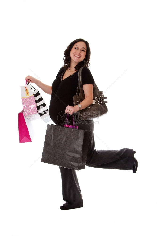 尽管美丽的快乐令人兴奋笑着微高加索孕妇黑发女人在走路时拿着购物袋并举起腿来被孤立女孩婴儿图片