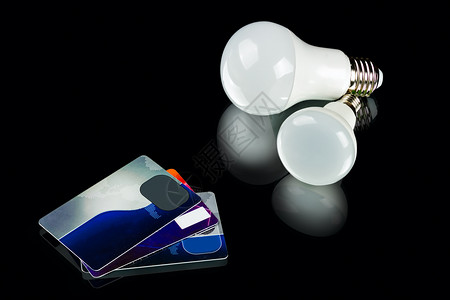 电气白色创新节能LED灯泡和黑底信用卡色背景的目图片