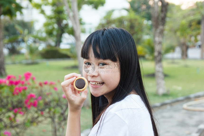 白色的在花园里吃巧克力饼干的泰国女孩子漂亮的图片