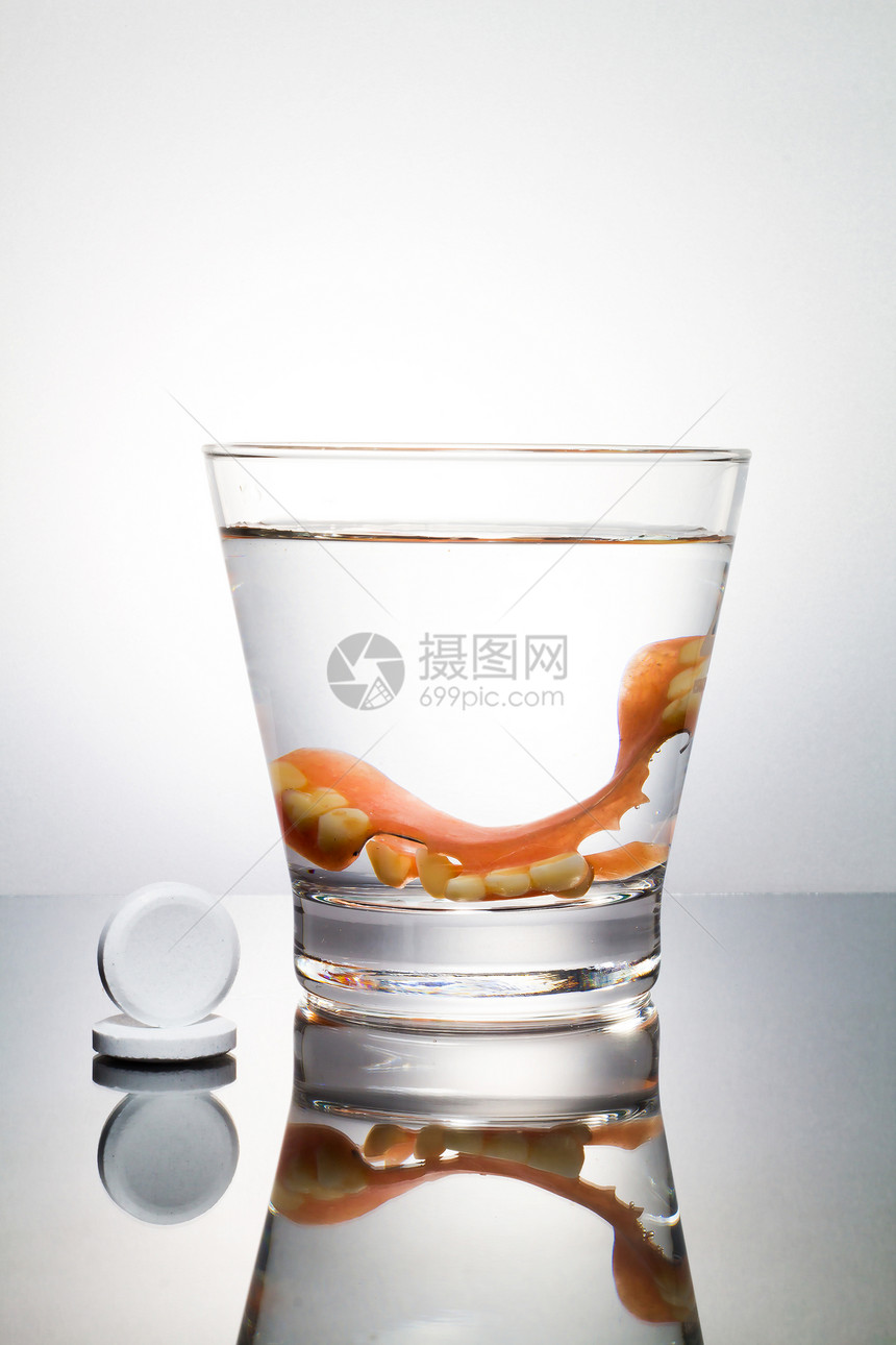 干净的在玻璃杯中用蓝色水清洗假牙保持卫生透明医疗的图片