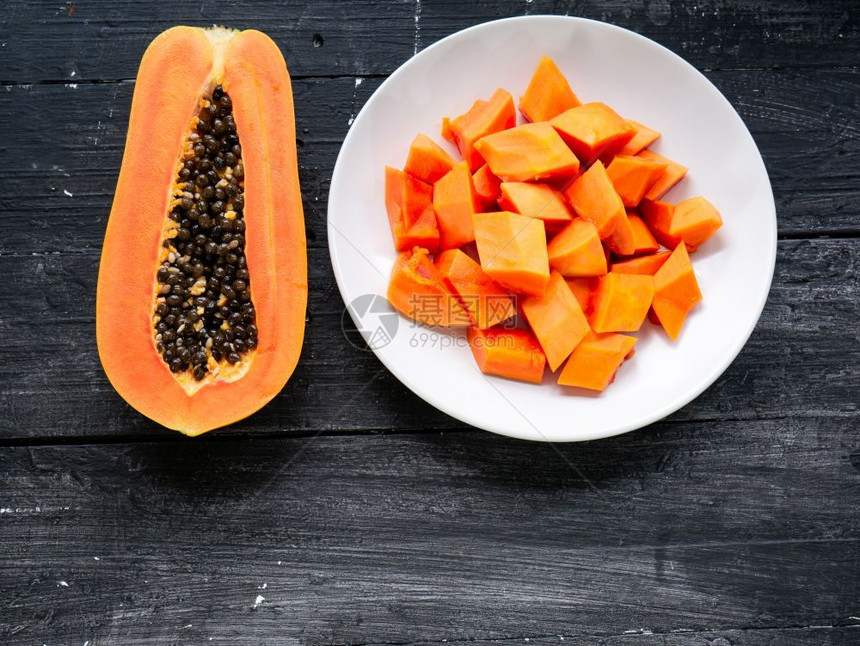 新鲜有机的切片熟木瓜水果的顶部视图半成木瓜果和黑本底白板上的碎块健康图片