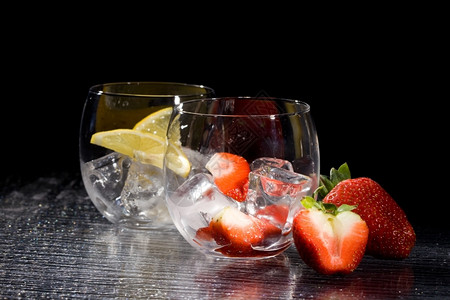 喝酒鬼寒冷的冰块上鲜草莓和柠檬的照片图片