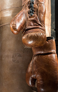 目的战斗机挂在拳袋旁边的旧棕色皮衣拳击手套经典的图片