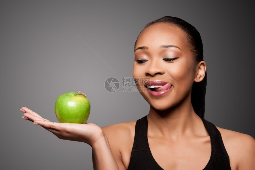 美丽的健康快乐地舔着手拿美味苹果的黑亚洲女人有机的哈基又美味图片