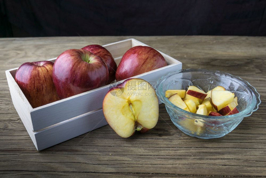 节食新鲜水果碗里有红苹木制桌上的盒子里有苹果图片