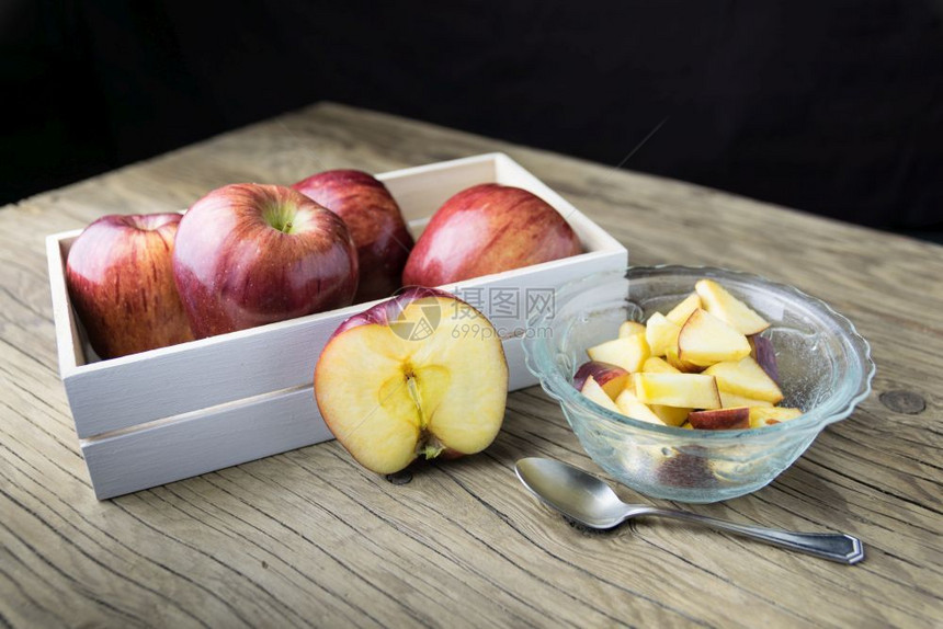 碗里有红苹果木制桌上的盒子里有苹果桌圆形的多汁图片