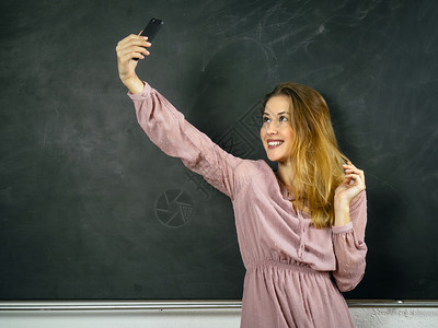 快乐的班级照片中一位美丽的学生在课堂上黑板前自拍正面图片