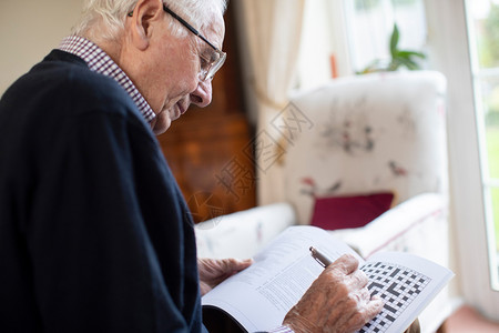 退休高级的年长者在家中玩填字猜谜游戏脑图片