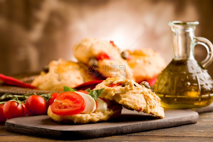 美味的油意大利面木制桌上塞满番茄和马扎里拉的自制美味披萨卷图片
