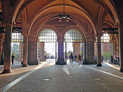 自行车运输在荷兰阿姆斯特丹的Rijksmuseum下走过建筑的图片