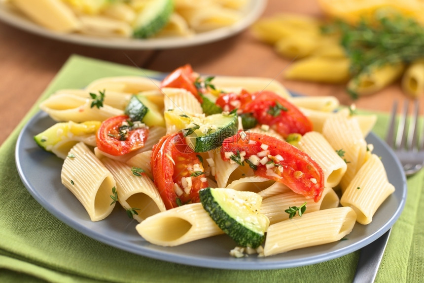 重点食物草本植蔬菜和面食盘配有烤菜和番茄配有百米和大蒜选择焦点将三分之一的焦点放在与Zucchini和番茄一道的意大利面碗中图片