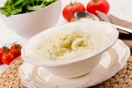 玉米面饺子罗马涅美味的玉米面意大利和白桌上蔬菜加汤子一顿饭背景