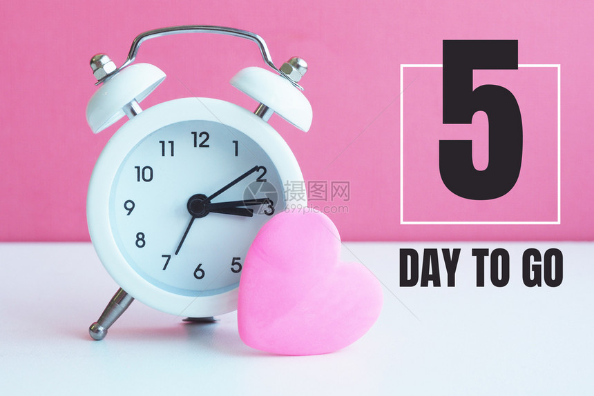 一个小白闹钟和粉红的心雕像5天后登记开幕桌子冬天图片