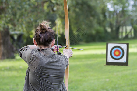 射击主要的射箭女孩弓箭手使用和头向目标背景