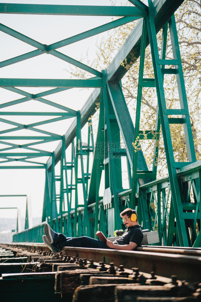 胡子悍马世界年轻建筑工人坐在一旁看本关于旧钢铁路桥的书坐着图片