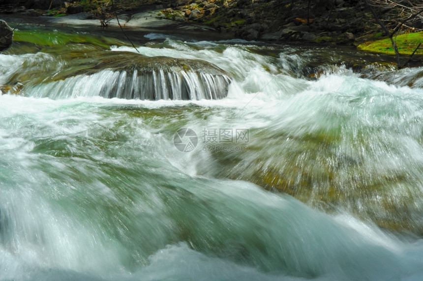自然赛车干净的清水从河床沿岩石和巨冲下河床形成快速径流和小瀑布走图片