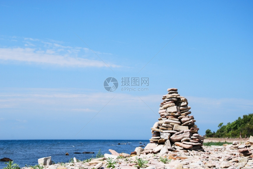 海岸的一块石头雕塑底有地平线和蓝水阳光色的图片