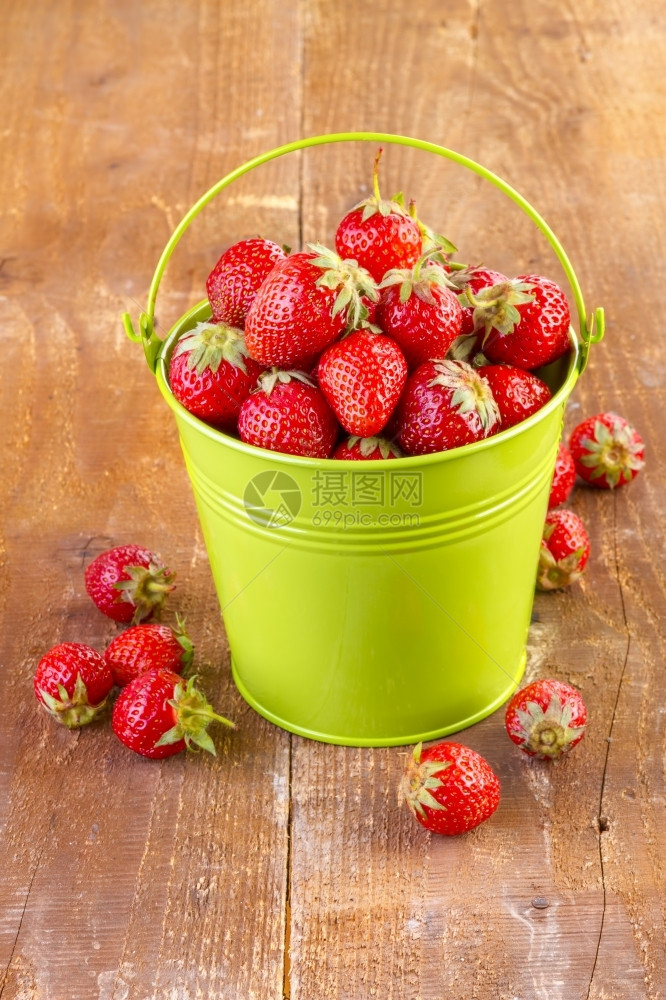 健康木头草莓在制背景的绿色金属桶中新鲜的图片