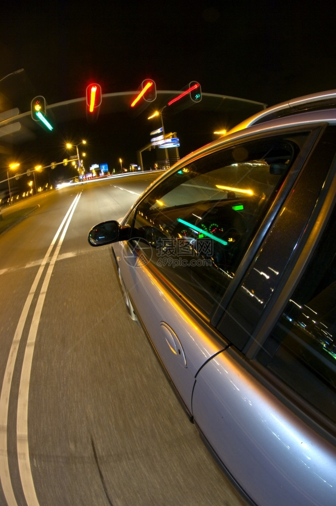 线条琥珀色镜子一辆汽车在夜间为交通灯的红而行驶图片