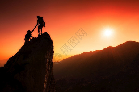 目标动机冒险登山者团队帮助高峰会在日落时一个奇妙的山地风景中携手合作图片