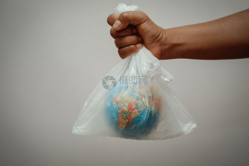 世界肮脏的家庭在灰色背景概念地球日上用塑料袋手握着地球图片