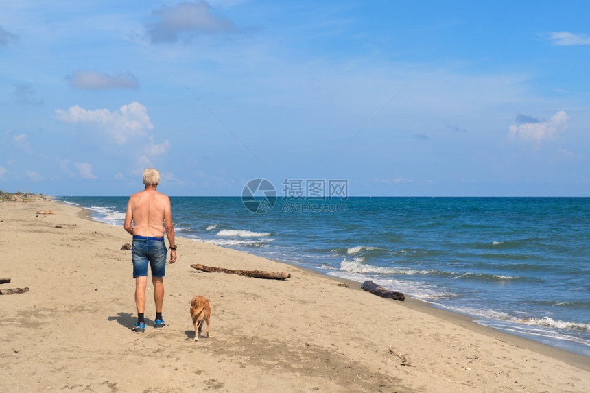 帽地中海欧洲男人和他的狗在科西嘉海滩图片