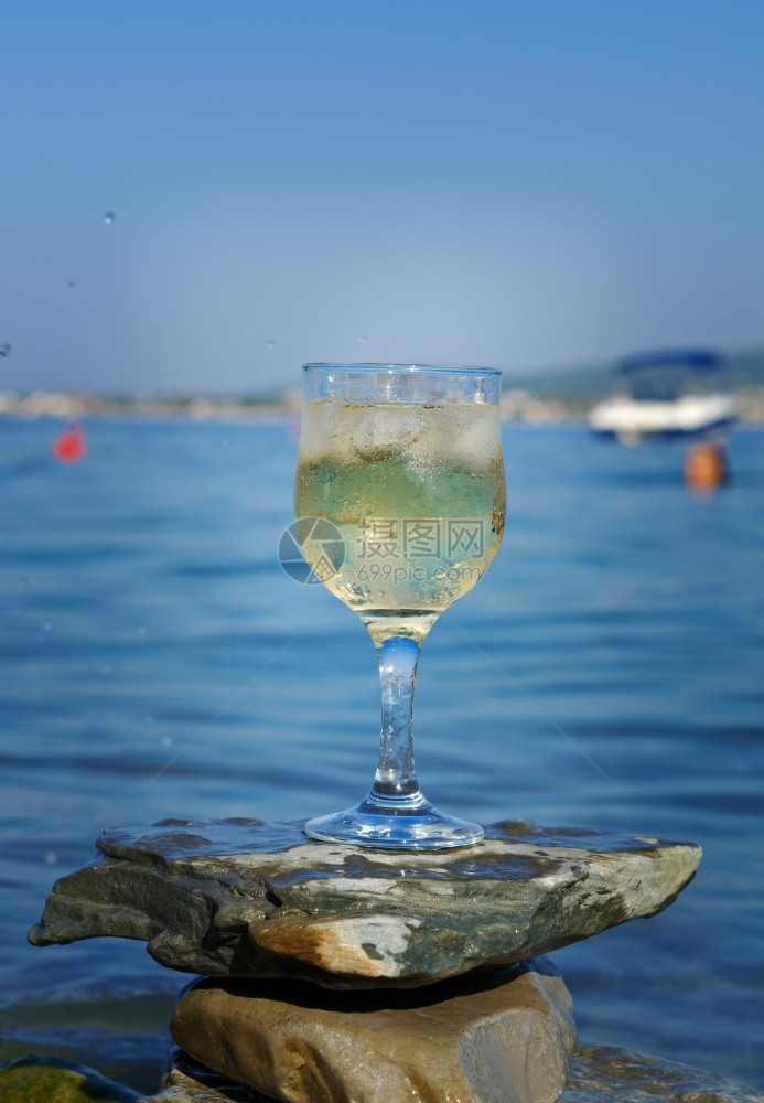 太阳海浪冲刷的岩石边杯白葡萄酒被海浪冲洗过野餐请享用图片