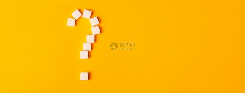 白色的以橙背景问号形状白糖立方体在橙色背景上被塑造成一个问题标记过量的成形图片