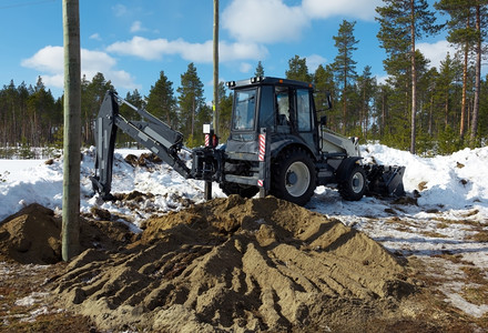 挖掘土机在冬季森林中挖掘高梁柱建造电线桶条白色的图片