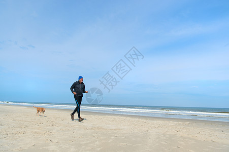 特谢林男人和狗在沙滩上奔跑背景