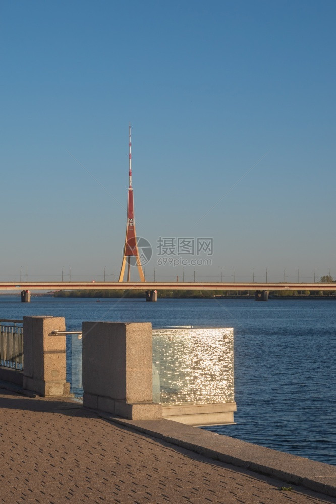 城市观看位于RIga的DaugavaPromenade在阳光明媚的春夜阳光和闪亮的水从玻璃阳台反射到南部水桥和Riga无线电台和图片