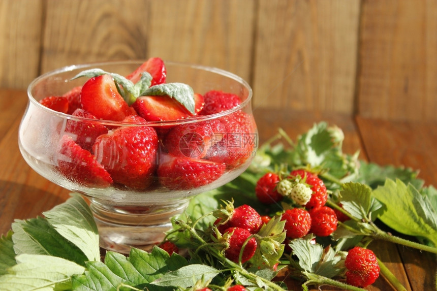 收成透明碗里的熟草莓和带叶子的串透明碗里的成熟草莓切片和带叶子的草莓串庄稼明亮的图片