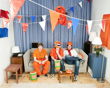 乐趣荷兰语三个幻想破灭的体育风扇坐在沙发上观看队的游戏服装图片