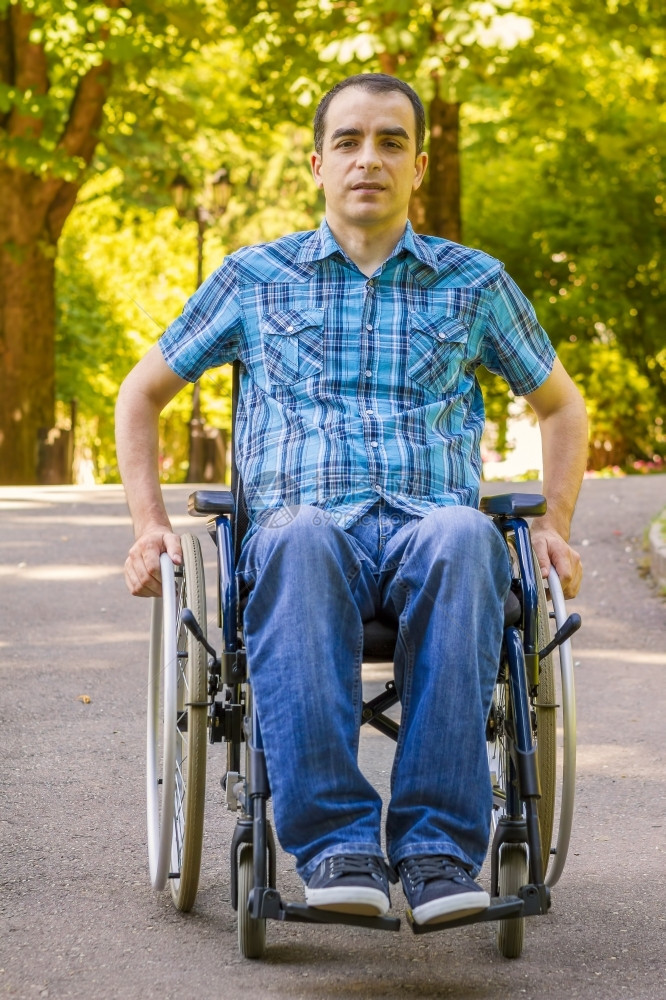 自由在城市公园坐轮椅的青年男子关心幸福图片