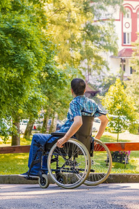 外部在城市公园坐轮椅的青年男子关心车轮图片