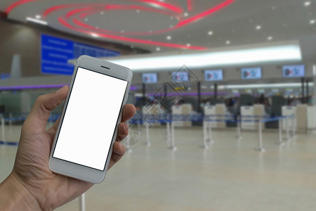 票手持智能电话空白屏幕和模糊的登入机场候室背景的一手男子飞机旅行图片