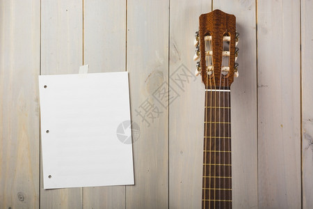 用吉他头顶卡在木墙上的空白音乐页花朵木制的水果图片