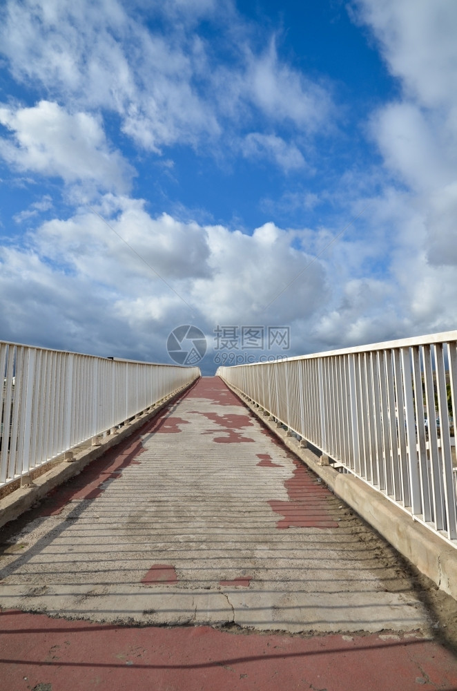 方向行人沿着一条有白色栅栏的肮脏混凝土大桥木板图片