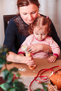 手工制作的孩子准备女人和儿一起装饰圣诞烤姜饼干与她小女儿结霜图片