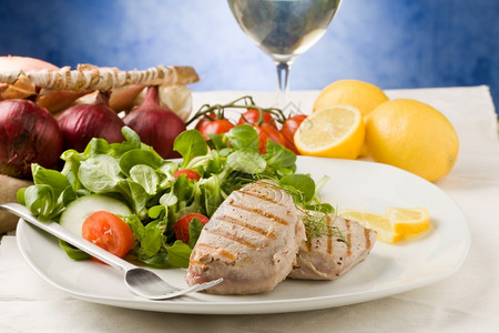 好的健康白色烤金鱼牛排和绿色木制餐桌上盐水图片