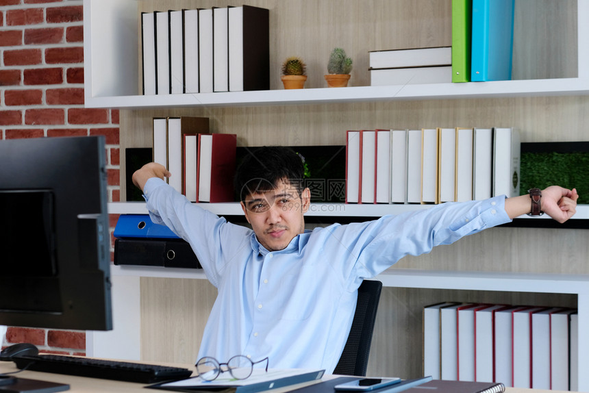 在线的工作场所桌子年轻的青亚洲人办公室男子在桌电脑室生活方式商业状况等工作时伸展身体以放松力图片