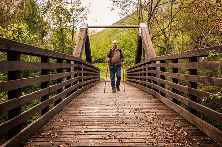 成年男子在山上徒步行在木桥上走徒步旅男人道图片