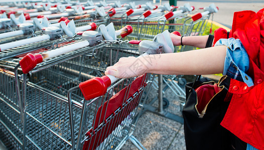 2016年3月日Auchan超市从一排购物车上下的女人零售消费者购物图片