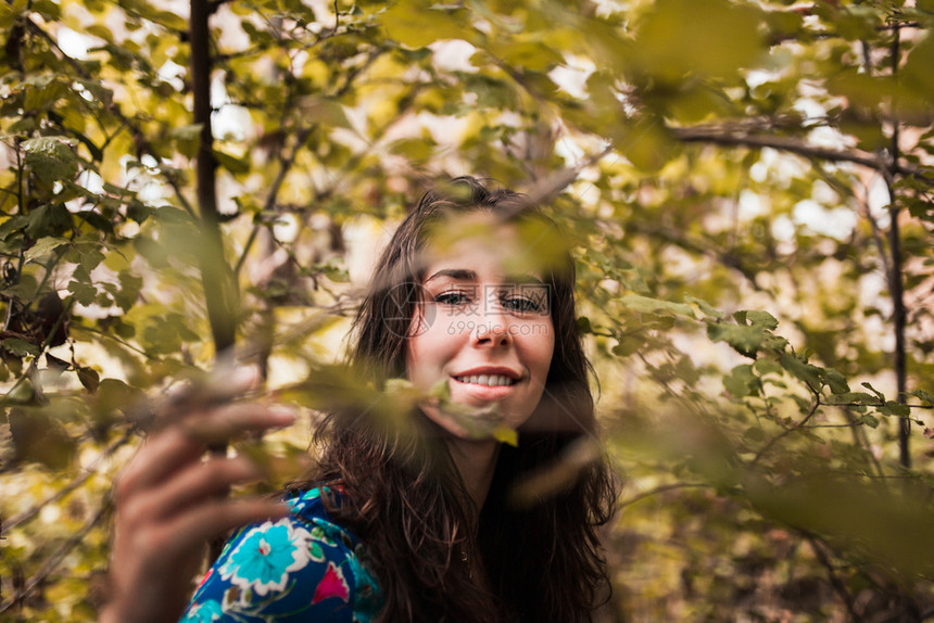 黑发春天年轻微笑的女士在森林中穿着衣服自然图片