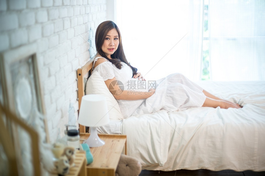 关心家期待有吸引力的怀孕亚洲妇女躺在床上抱着肚子图片