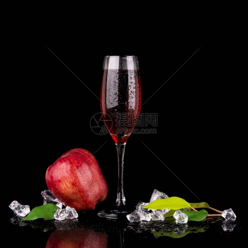 热带红苹果和一杯香槟黑色背景的底一种新鲜图片