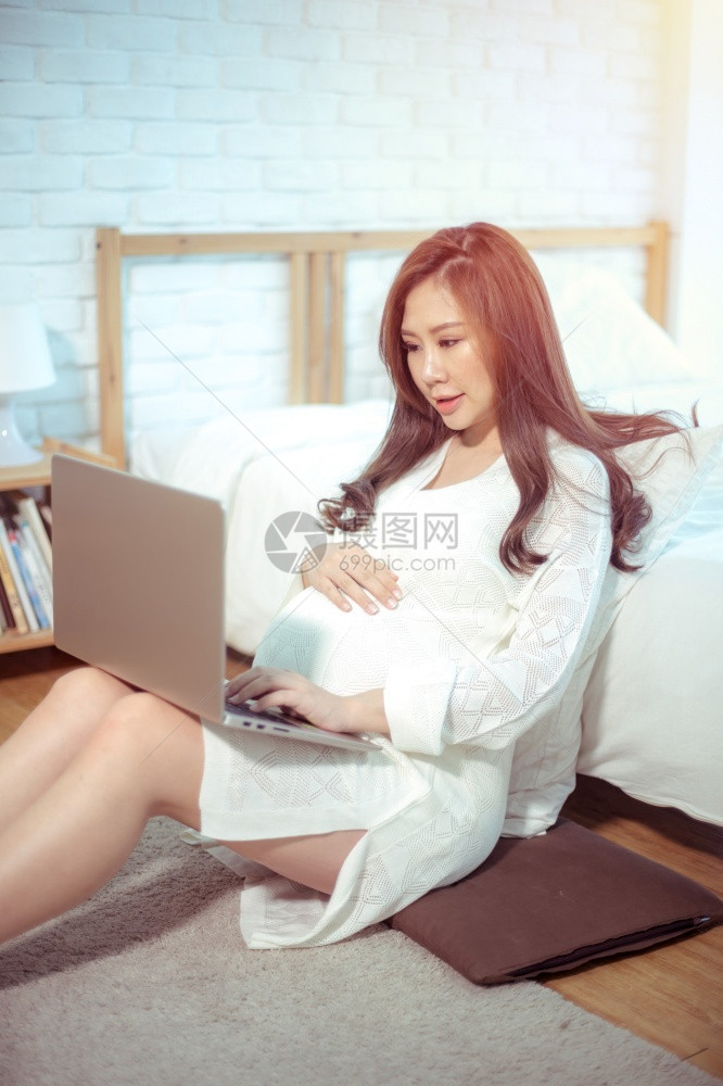 淑女使用笔记本电脑坐在家中床上的怀孕亚洲妇门户14坐着图片