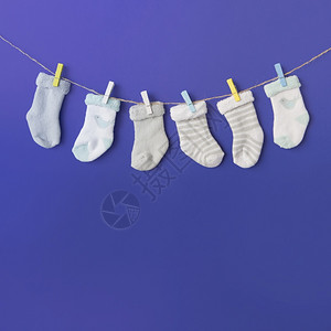 晾衣绳人们高的蓝色背景下不同类型婴儿的袜套挂衣绳图片