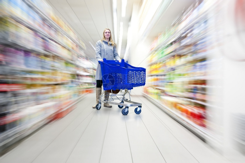 自信的女人在超市里用她的购物车做杂货选择什么动态的消费者运图片